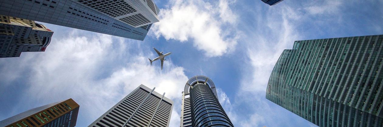 View from below of a circle of skyscrapers with a plane flying above