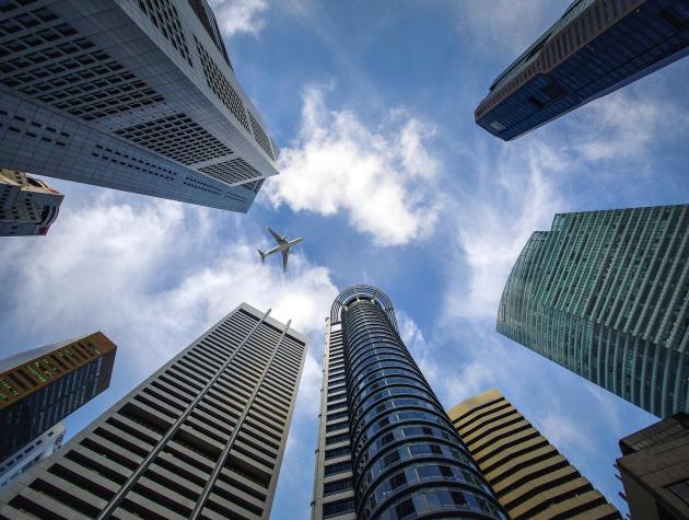 View from below of a circle of skyscrapers with a plane flying above